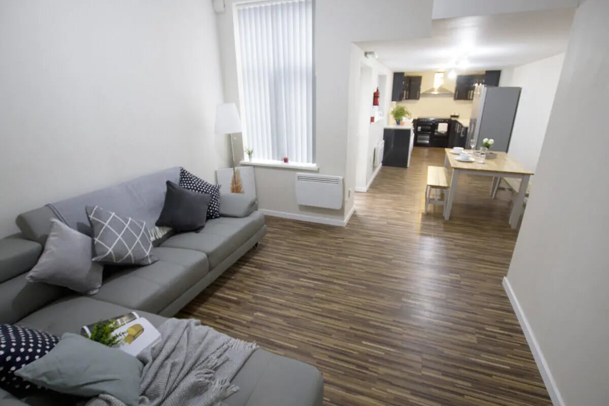 Grey sofa patterned cushions wooden floor dining area living room at 6 Bedroom House at 31, Deramore Street in Manchester Student Accommodation