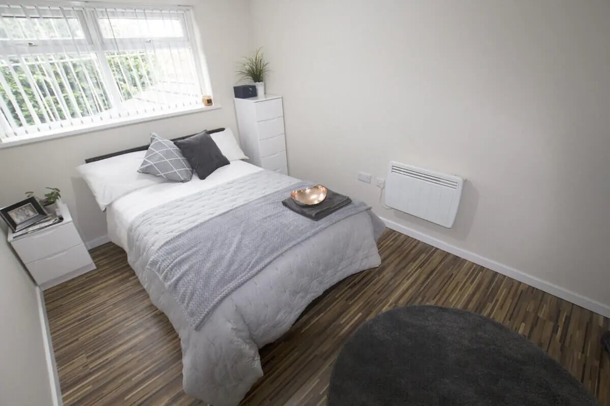 Bed with grey blanket dresser and window Bedroom at 6 Bedroom House at 31, Deramore Street in Manchester Student Accommodation