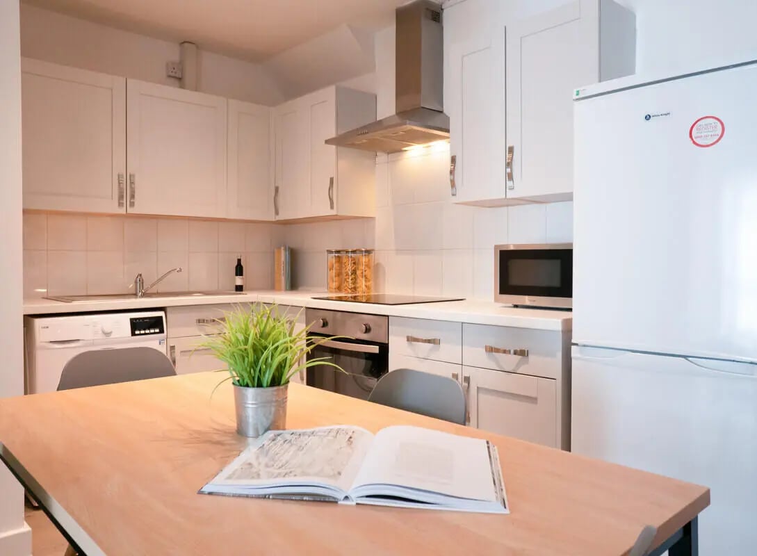 Kitchen with white cabinets fridge microwave and table kitchen at 5 Bedroom House at Flat 1, 331, Dickenson Road in Manchester Student Accommodation