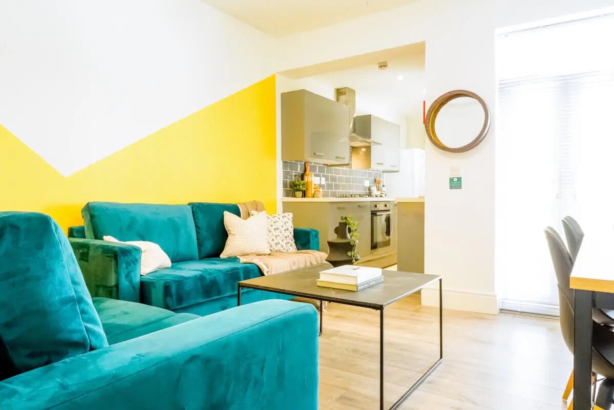 Teal sofas coffee table books living room kitchen at 5 Bedroom House at 19, Driffield Street in Manchester Student Accommodation