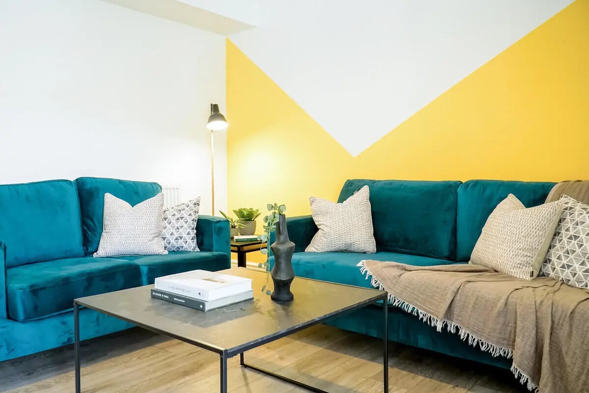 Two teal couches coffee table and yellow wall living room at 6 Bedroom House at 49, Ruskin Avenue in Manchester Student Accommodation