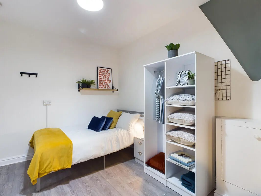 Bed with yellow throw and wardrobe bedroom at 6 Bedroom House at 10, Richmond Road in Lincoln Student Accommodation