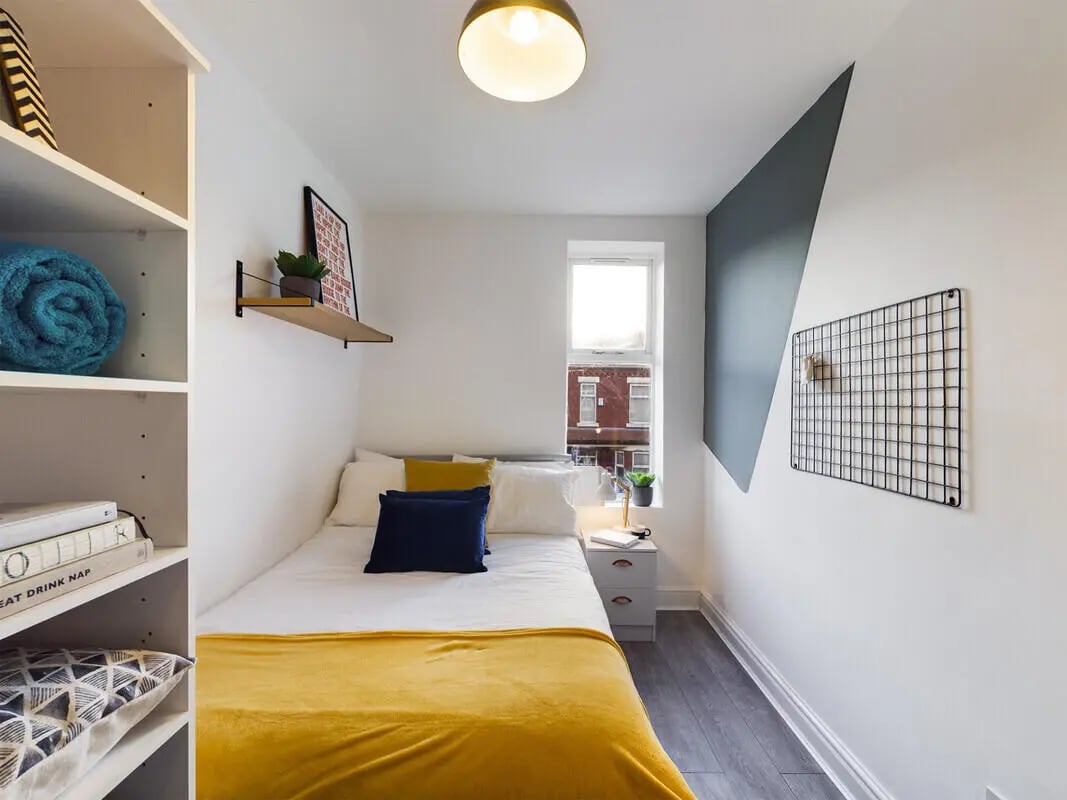 Bed with yellow blanket blue pillows shelf bedroom at 6 Bedroom House at 10, Richmond Road in Lincoln Student Accommodation