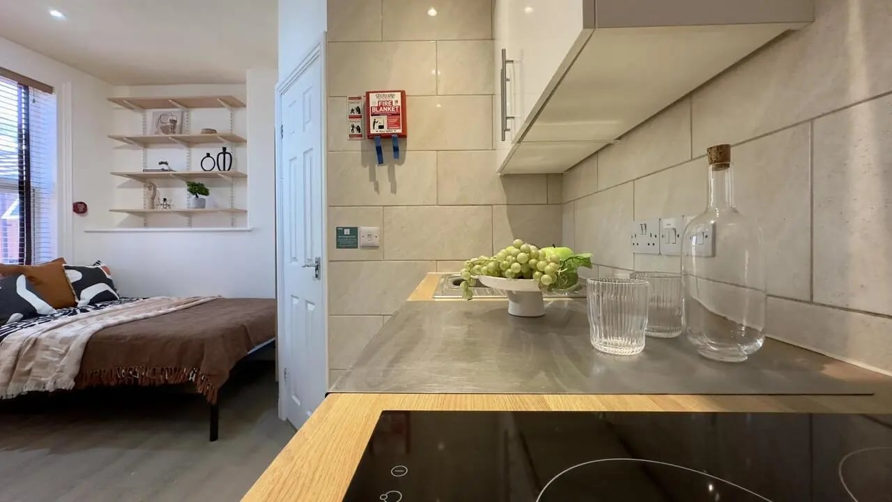 Bed with pillows shelves and kitchen counter kitchen at 6 Bedroom House at 12, Studios at, Richmond Road in Lincoln Student Accommodation