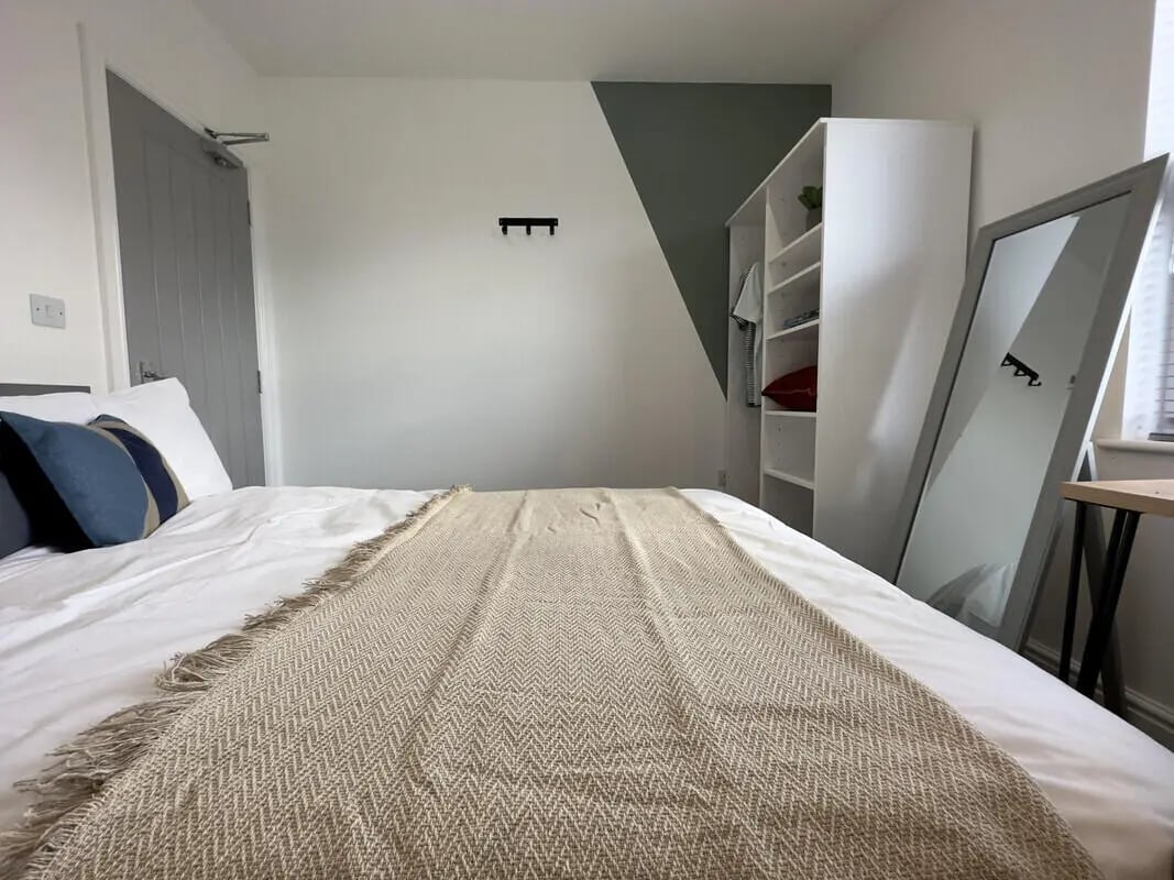 Bed with blankets pillows white wardrobe large mirror bedroom at 6 Bedroom House at 43, Monks Road in Lincoln Student Accommodation