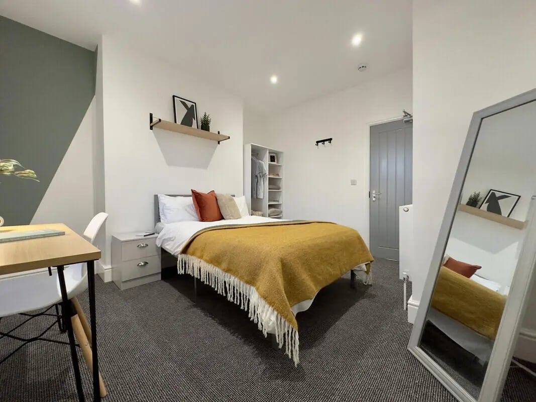 Bed with yellow throw and desk bedroom at 6 Bedroom House at 45, Monks Road in Lincoln Student Accommodation