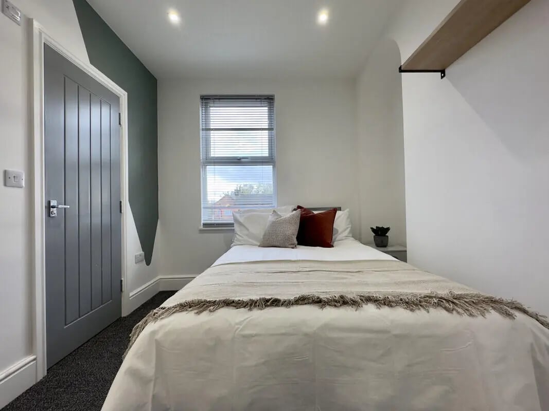 Bed with white bedding pillows and plant Bedroom at 6 Bedroom House at 45, Monks Road in Lincoln Student Accommodation