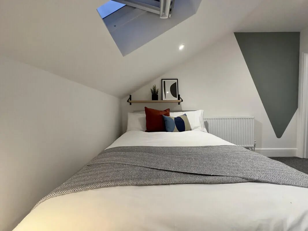 Bed with pillows artwork shelf and skylight bedroom at 6 Bedroom House at 45, Monks Road in Lincoln Student Accommodation