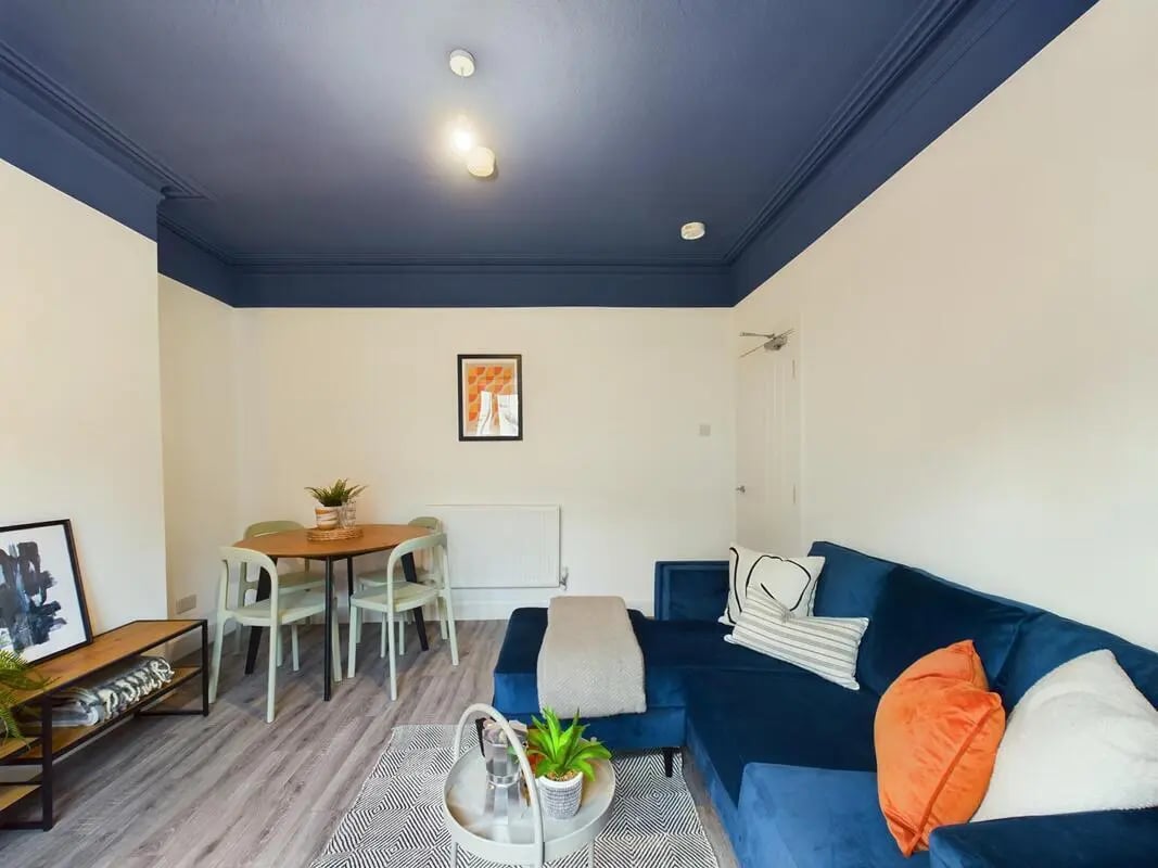 Blue sofa dining table and chairs living room at 6 Bedroom House at 32, Monks Road in Lincoln Student Accommodation