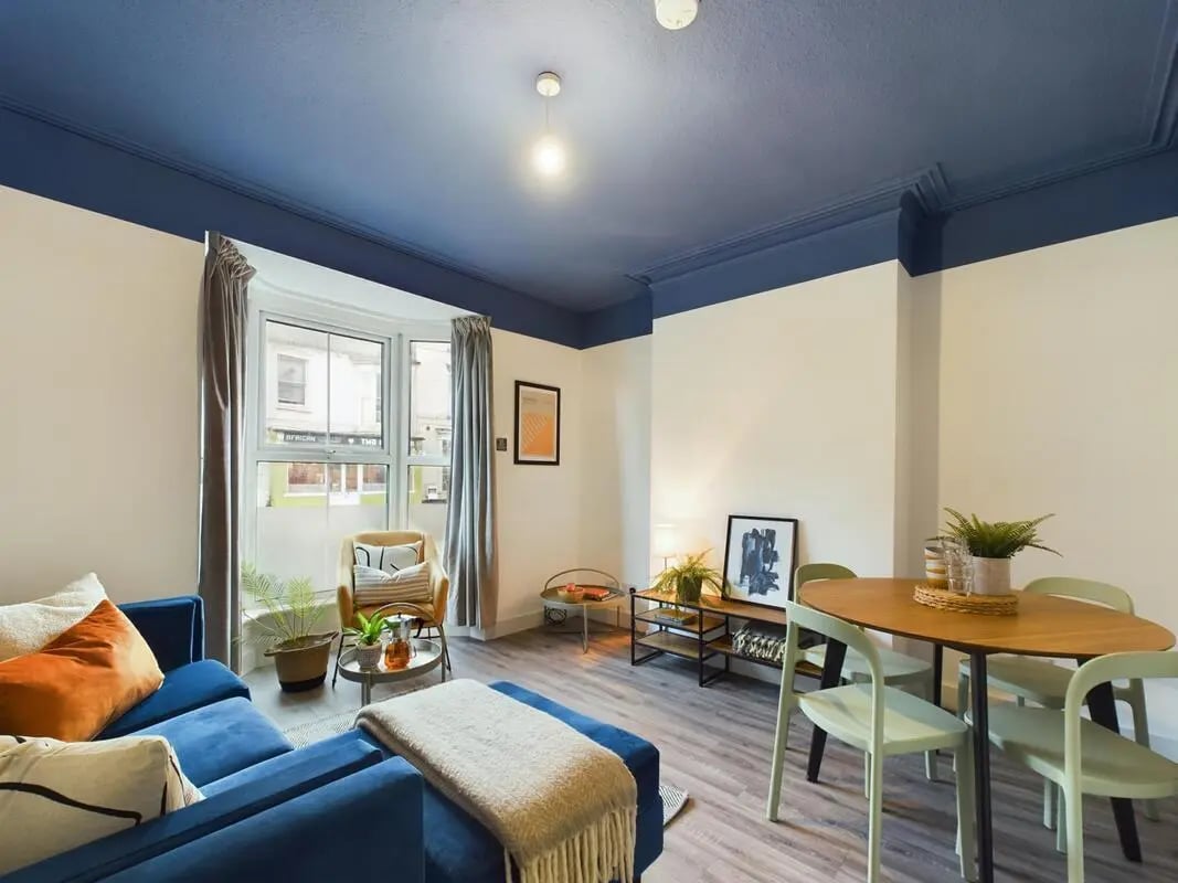 Blue sofa dining table and chairs living room at 6 Bedroom House at 32, Monks Road in Lincoln Student Accommodation