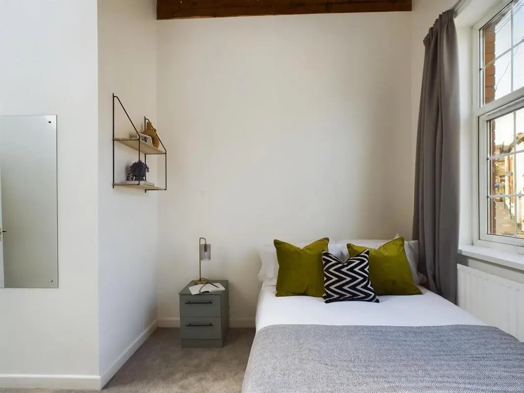 Bed with green pillows and gray blanket bedroom at 9 Bedroom House at 19A, Bower Road in Sheffield Student Accommodation