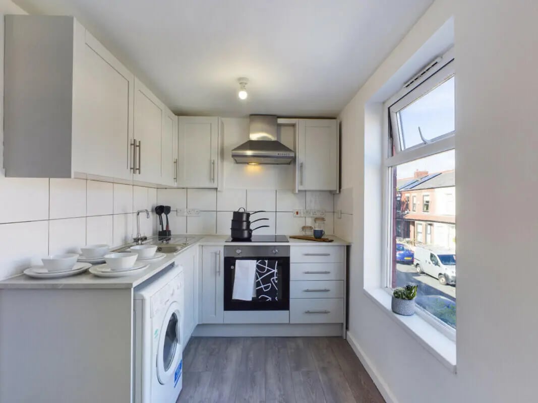 White cabinets washing machine stove bowls kitchen at 4 Bedroom House at 75, Saxony Road in Liverpool Student Accommodation