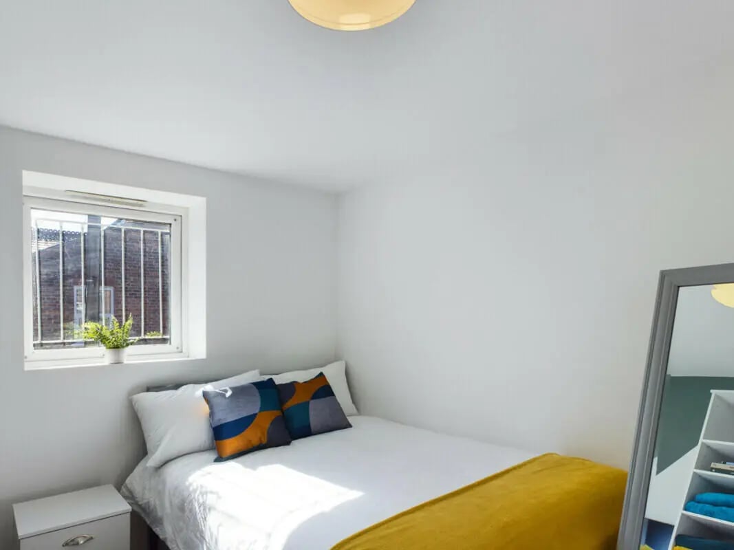 Bed white linens patterned pillows yellow throw mirror bedroom at 4 Bedroom House at 75, Saxony Road in Liverpool Student Accommodation