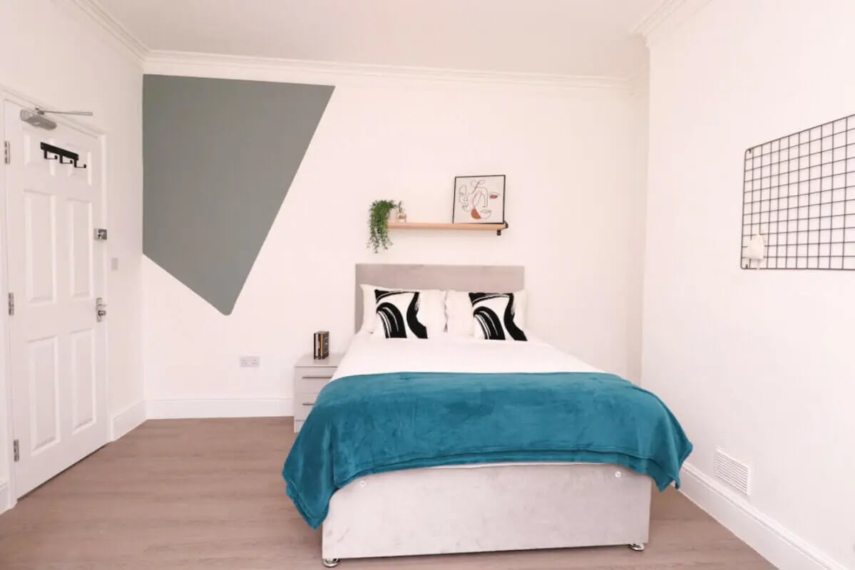 Bed with teal blanket and graphic pillows bedroom at 5 Bedroom House at 99, Monks Road in Lincoln Student Accommodation