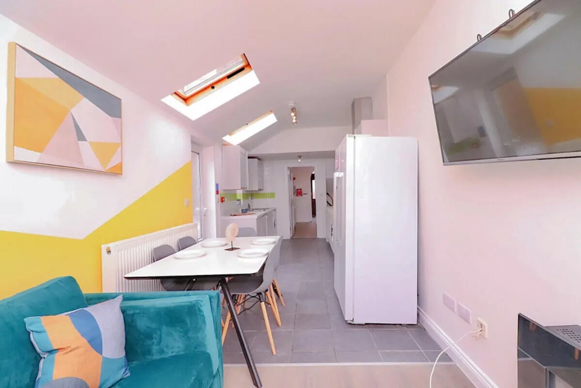 Sofa dining table kitchen fridge television living area at 5 Bedroom House at 99, Monks Road in Lincoln Student Accommodation