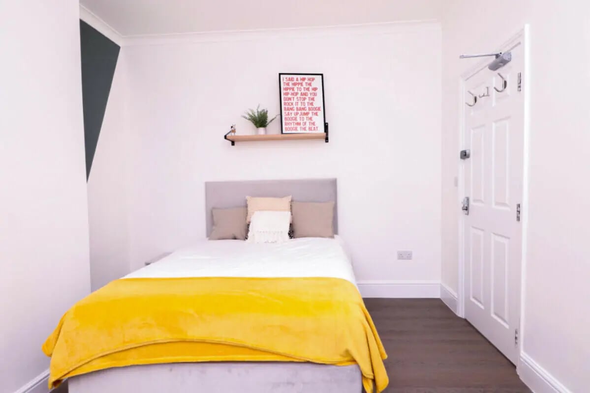 Bed with yellow blanket and pillows Bedroom at 5 Bedroom House at 99, Monks Road in Lincoln Student Accommodation