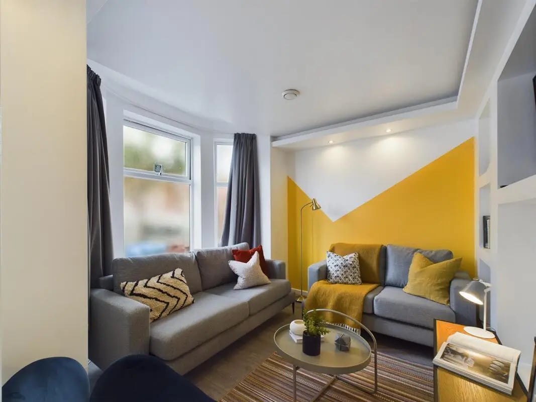 Two grey sofas with cushions and throws living room at 6 Bedroom House at 174, ACOMB STREET in Manchester Student Accommodation
