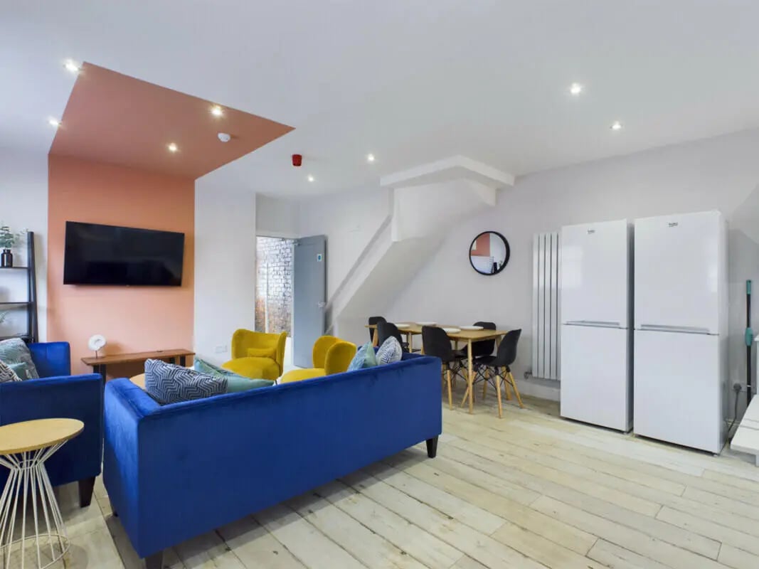 Blue sofa yellow chairs two fridges dining table living area at 8 Bedroom House at 211, Molyneux Road in Liverpool Student Accommodation