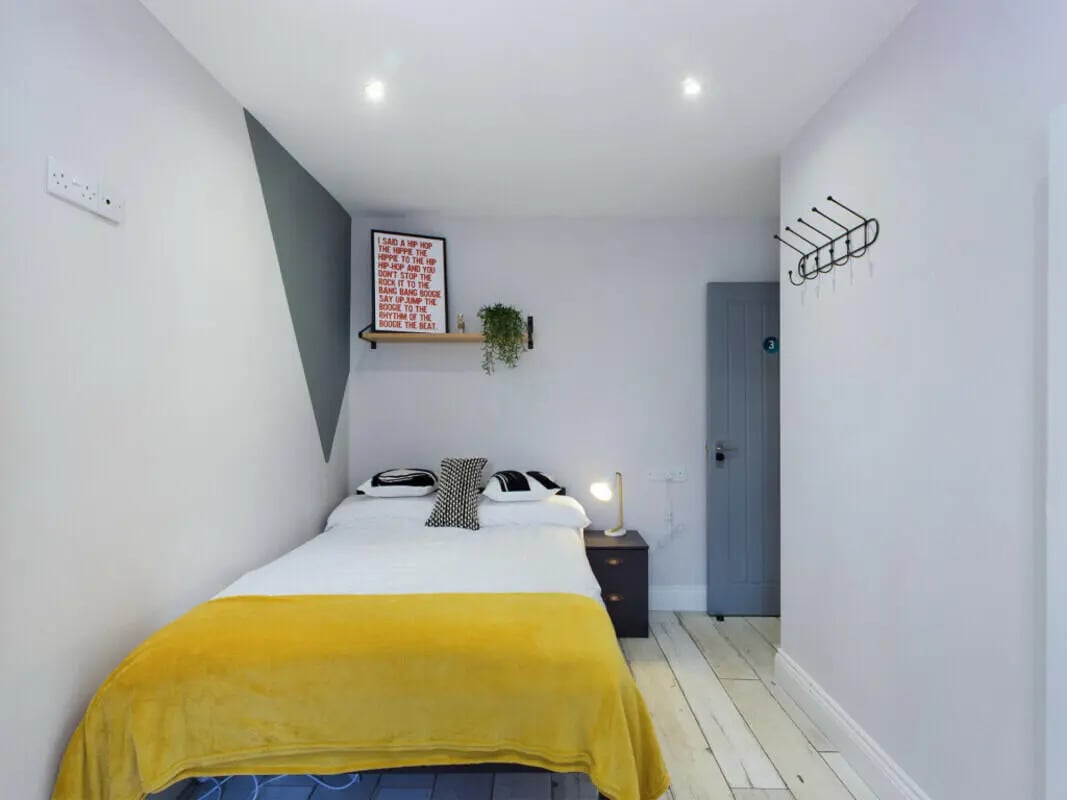 Bed with yellow blanket and nightstand bedroom at 8 Bedroom House at 211, Molyneux Road in Liverpool Student Accommodation