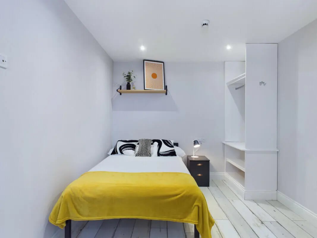 Bed yellow blanket black pillows bedside cabinet bedroom at 8 Bedroom House at 211, Molyneux Road in Liverpool Student Accommodation