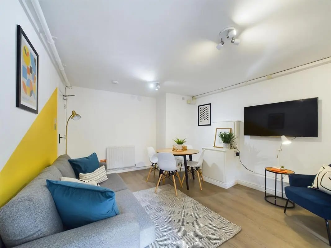 Grey sofa dining table chairs and television living room at 4 Bedroom House at 75, West Parade in Lincoln Student Accommodation