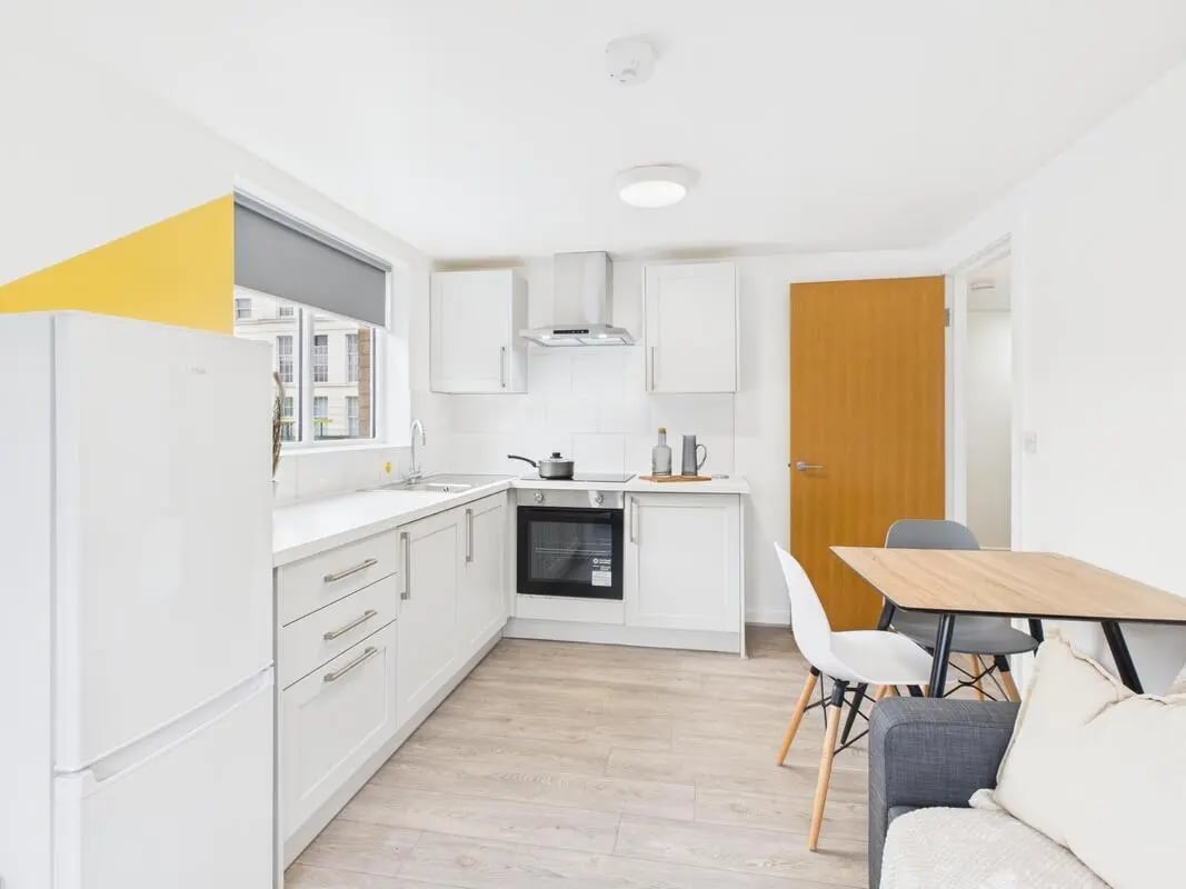 White kitchen with fridge oven dining table living room at 2 Bedroom House at Flat 1, Grove Street Studios, The Groves in Liverpool Student Accommodation