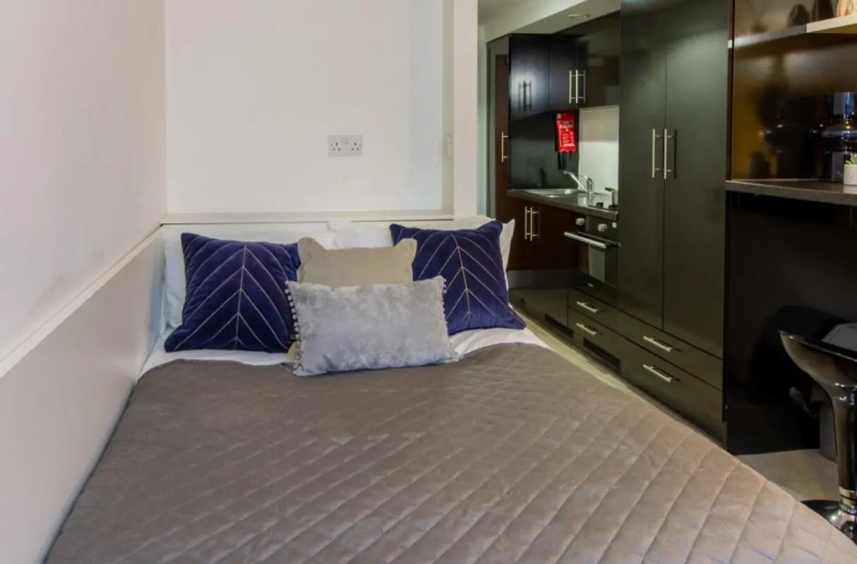 Bed with pillows and quilt kitchen area bedroom at Bowman House in Nottingham Student Accommodation