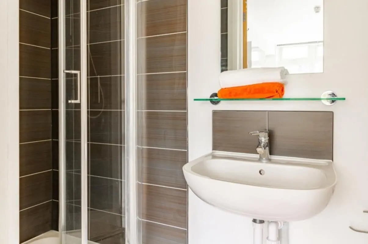 Shower cubicle sink and folded towels bathroom at Portobello Garrow House in London Student Accommodation