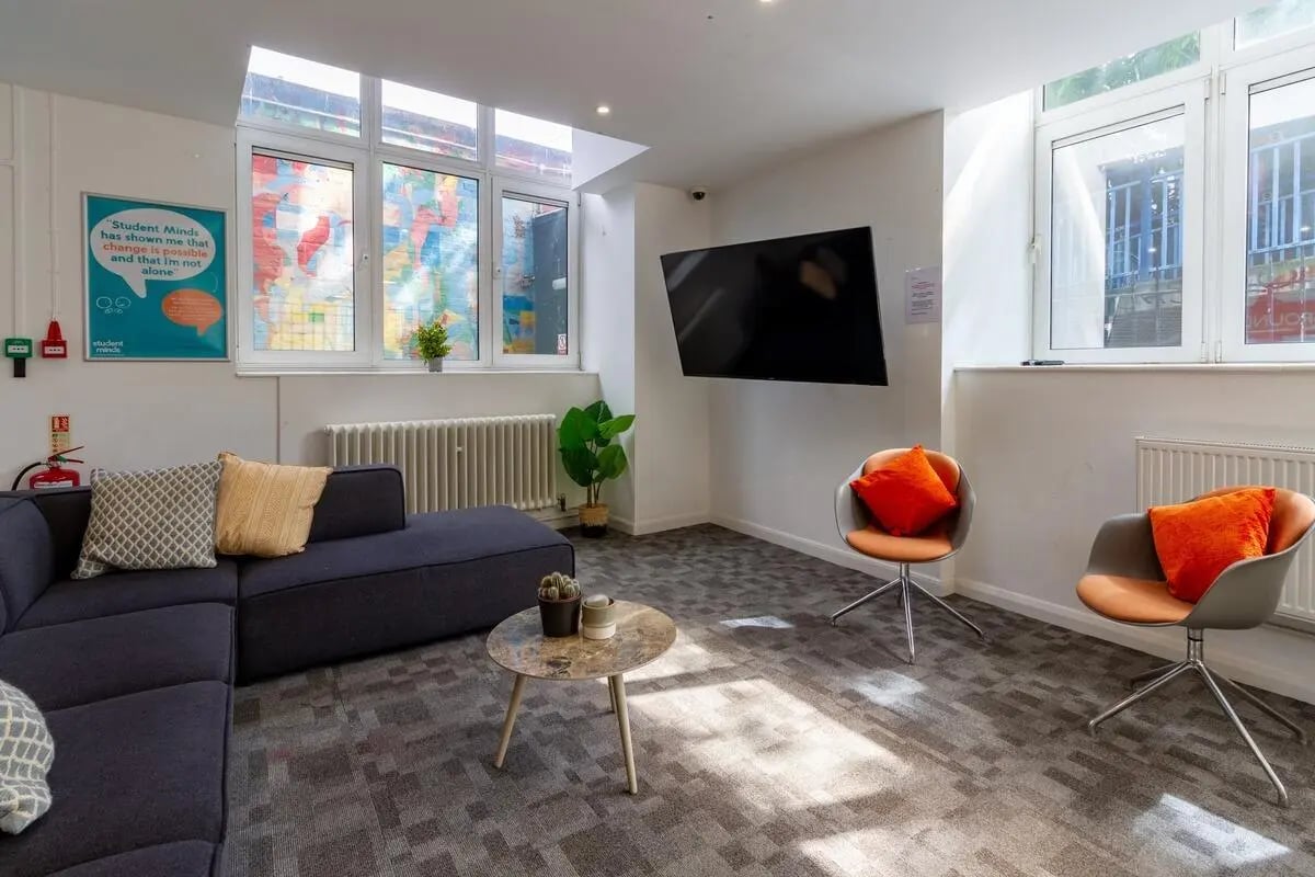 Sofa chairs table television map poster fireplace common area at Portobello Garrow House in London Student Accommodation