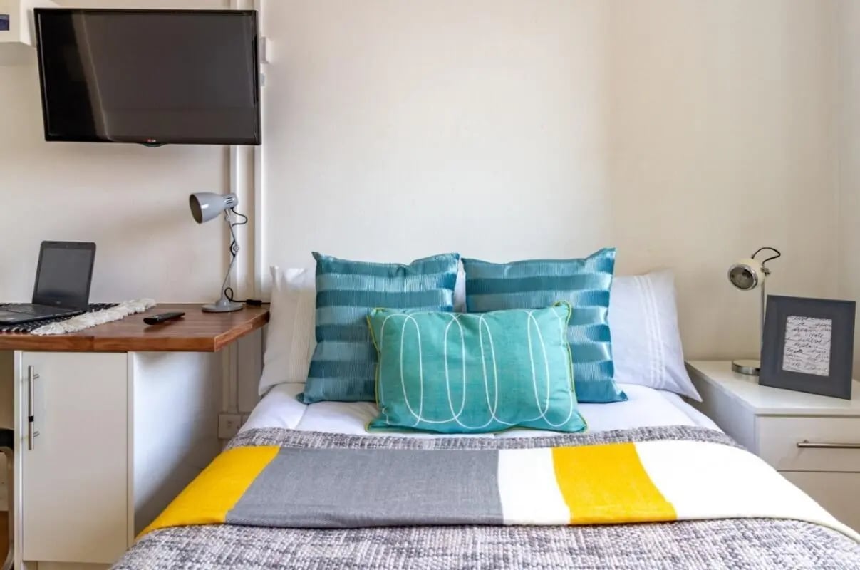 Bed with pillows desk laptop TV bedroom at Portobello Garrow House in London Student Accommodation