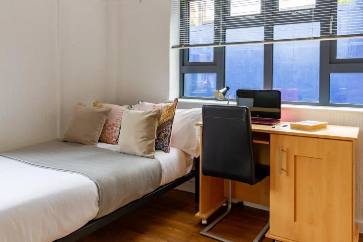 Bed pillows desk chair laptop study area at Surrey Quays Landale House in London Student Accommodation