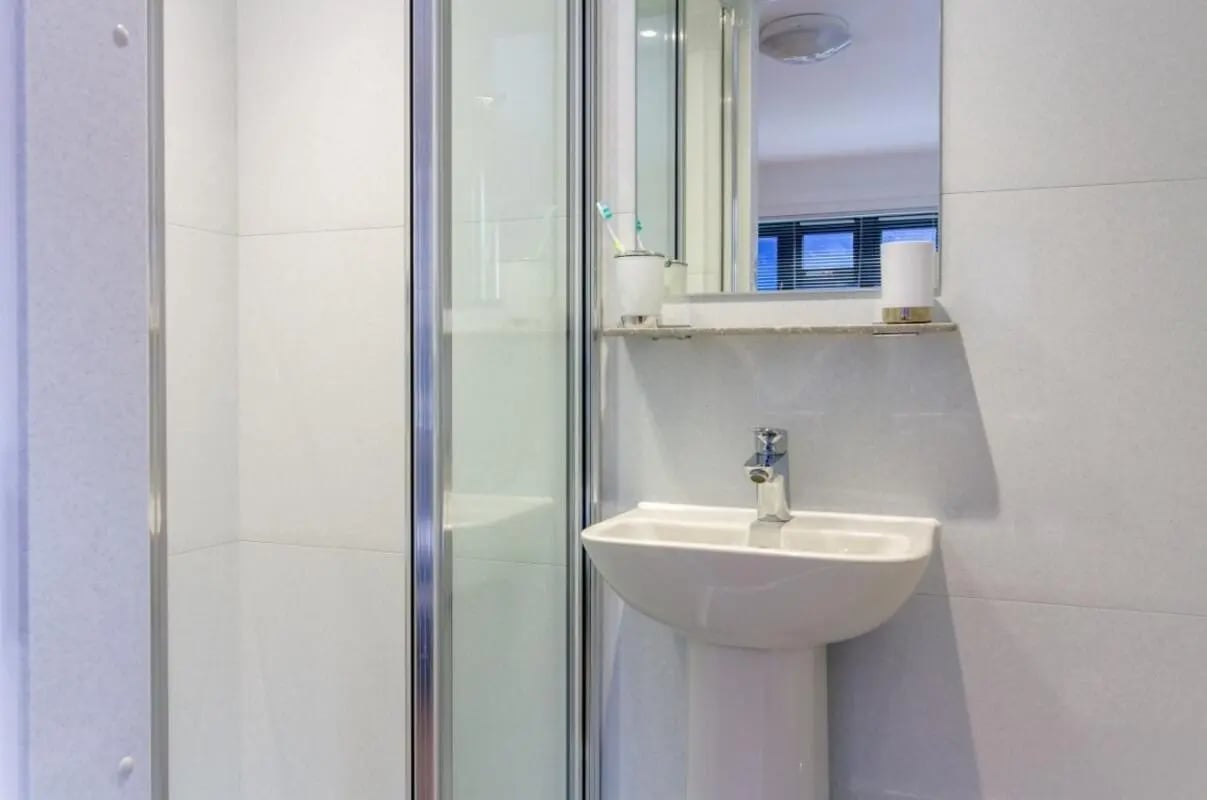Shower cubicle pedestal sink and mirror bathroom at Surrey Quays Landale House in London Student Accommodation
