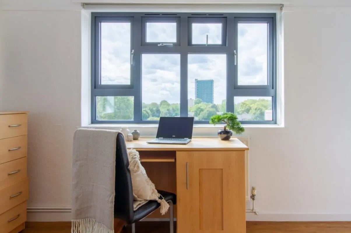 Desk with laptop blanket cushion bonsai study area at Surrey Quays Landale House in London Student Accommodation