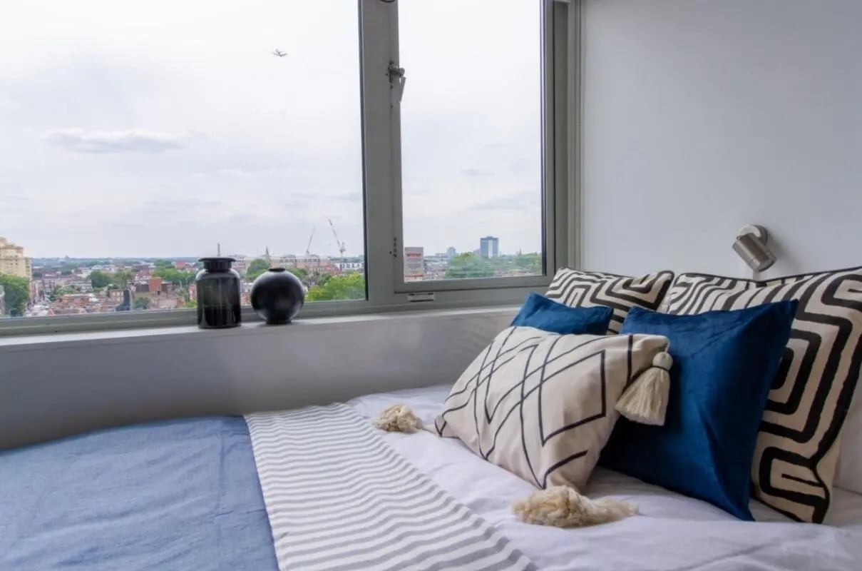 Bed with pillows and cityscape view bedroom at Chelsea Lightfoot Hall in London Student Accommodation