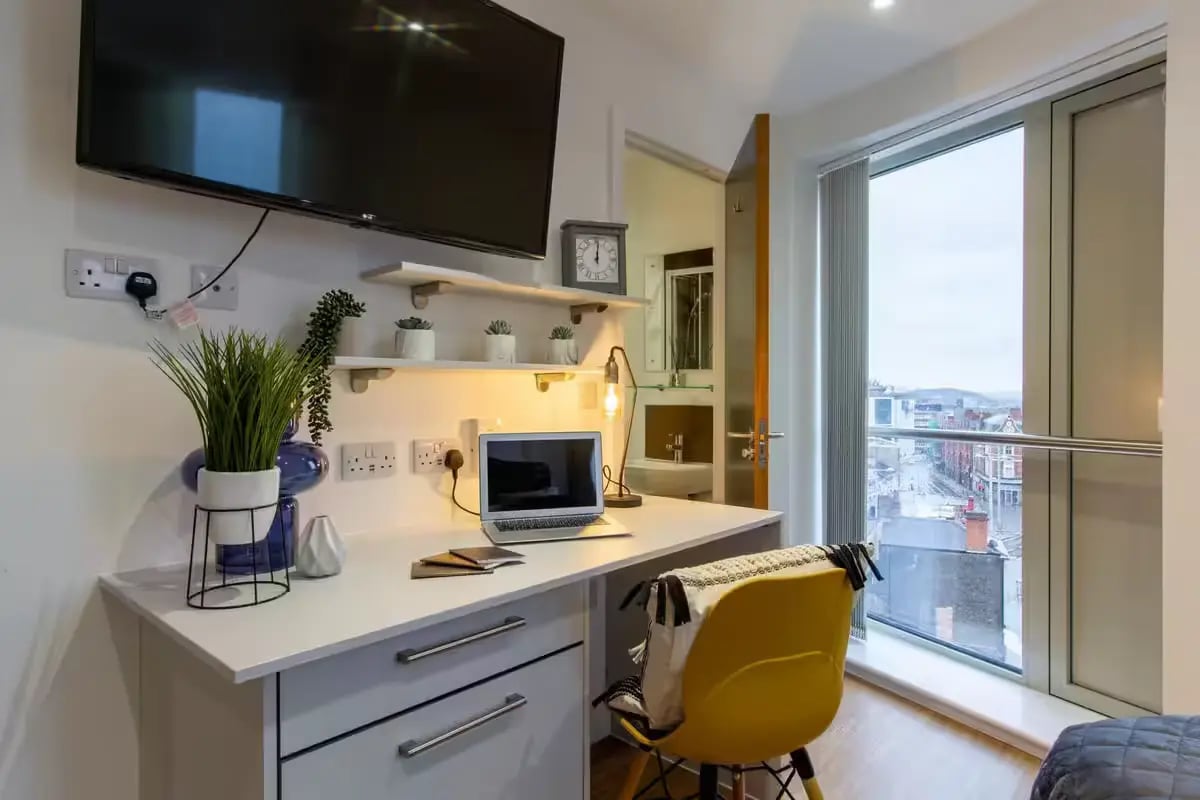 Desk with laptop, chair, shelves, TV, view, study area at Orbital in Nottingham Student Accommodation