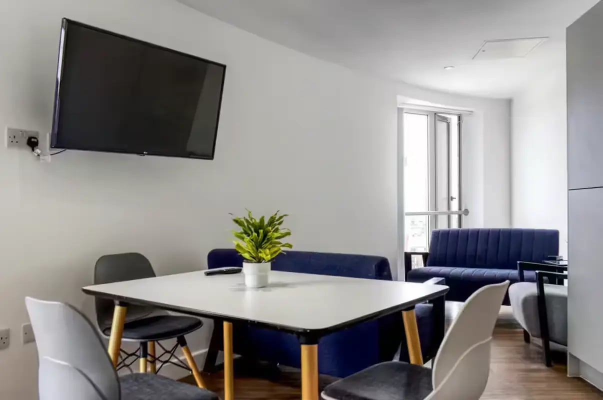 Table chairs plant sofa TV living room at Orbital in Nottingham Student Accommodation