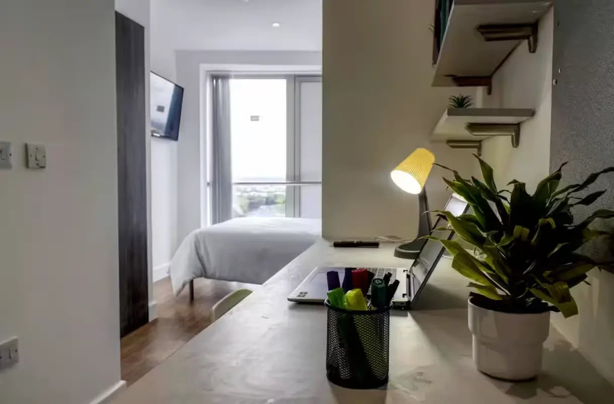 Desk with laptop plant pens lamp and bed Bedroom at Orbital in Nottingham Student Accommodation