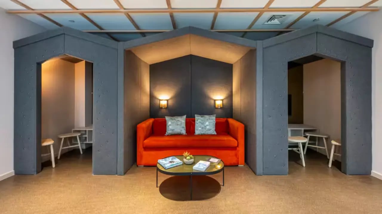 Orange couch with pillows coffee table study nooks living room at Flora Building - Hoxton in London Student Accommodation
