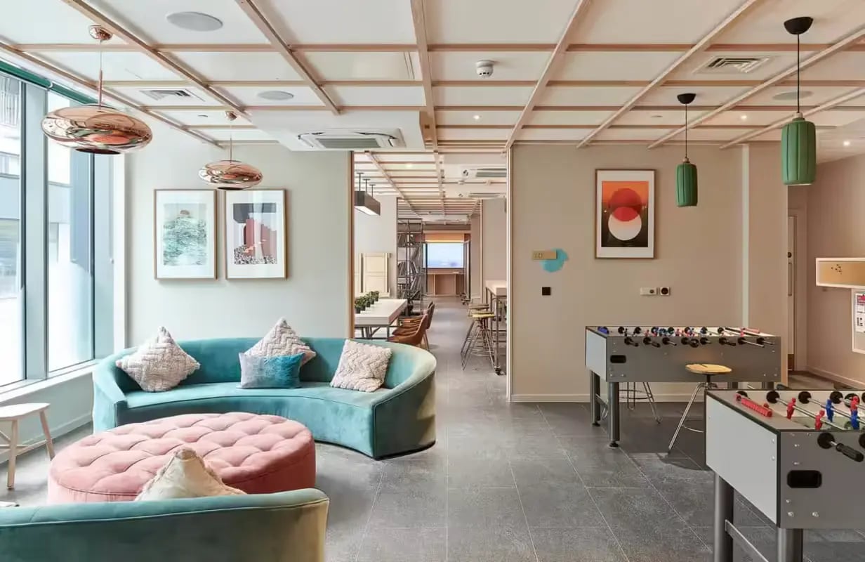 Curved sofa foosball tables modern lounge living area at Flora Building - Hoxton in London Student Accommodation