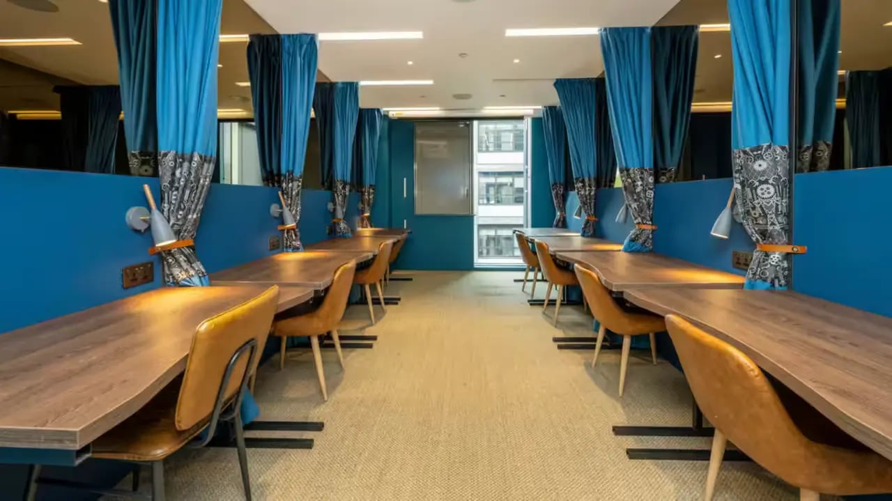 Desks chairs and blue curtains study area at Flora Building - Hoxton in London Student Accommodation