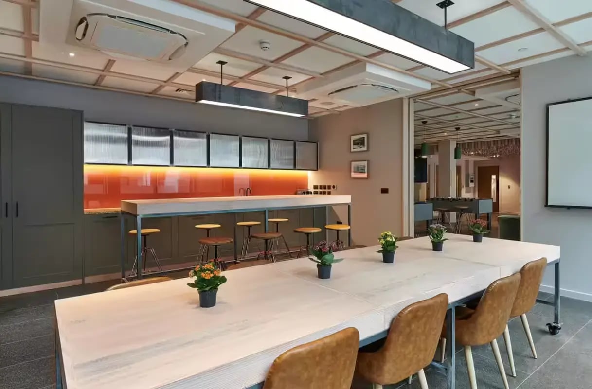 Long table chairs bar stools kitchen area common room at Flora Building - Hoxton in London Student Accommodation