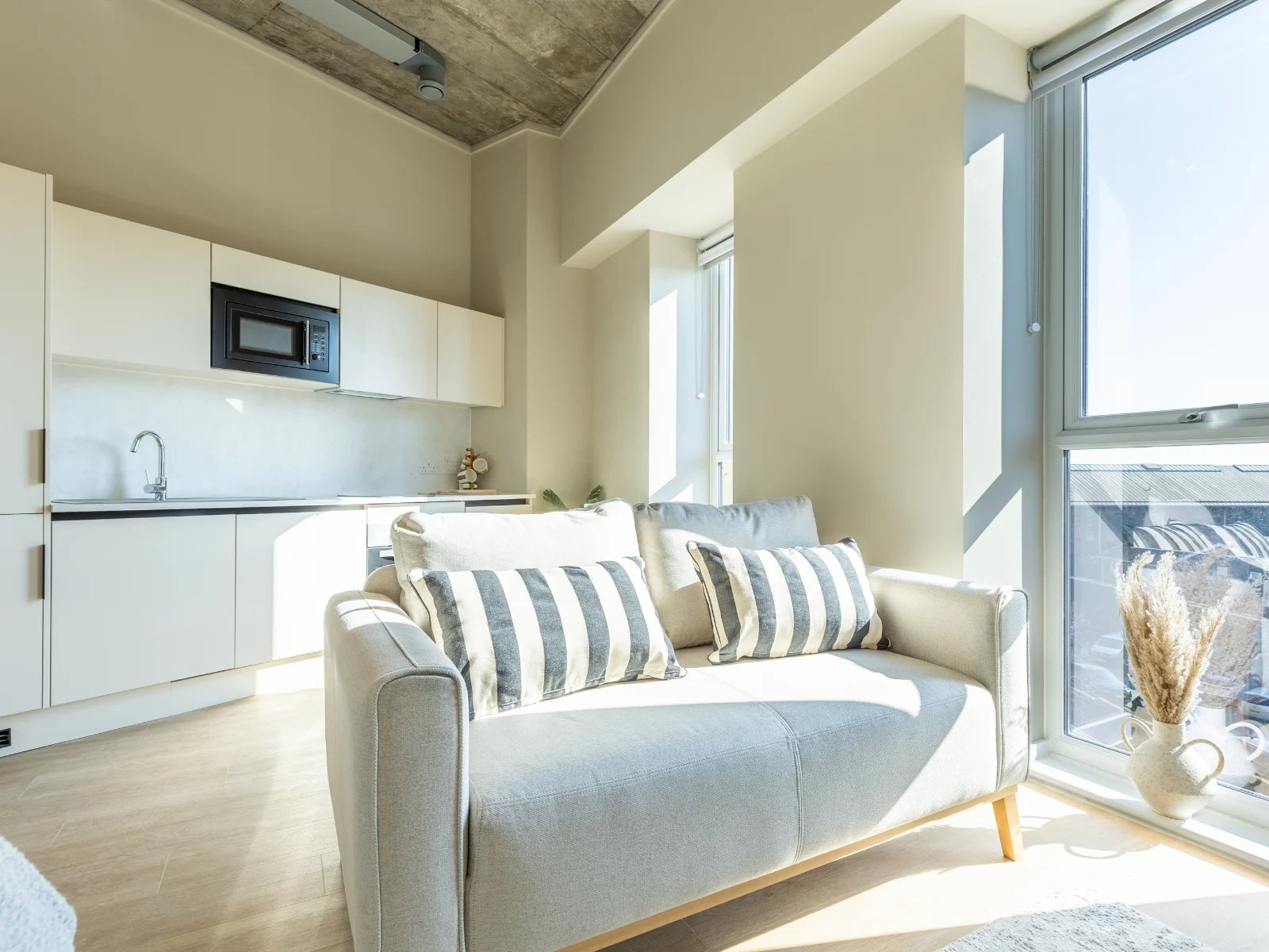 Sofa with striped pillows and modern kitchen living room at Fitz and Knox in Cardiff Student Accommodation