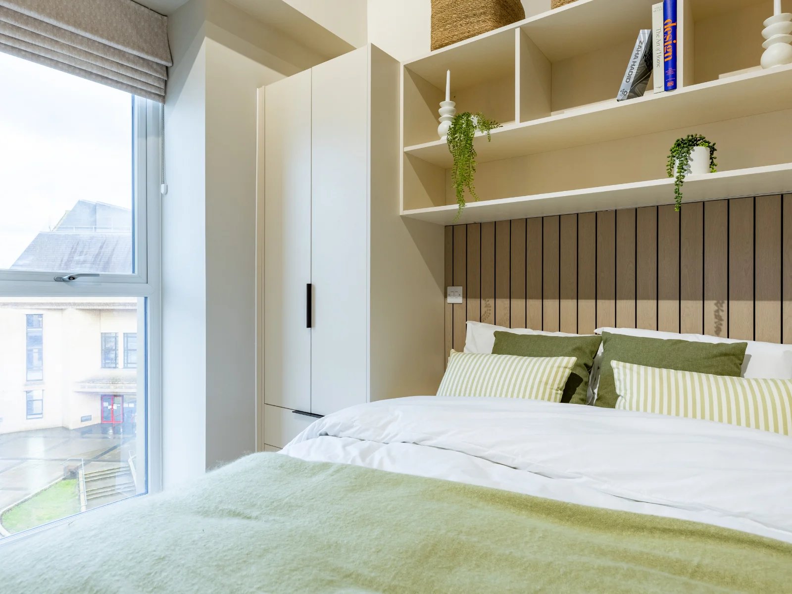 Bed with green pillows wardrobe and shelves bedroom at Fitz and Knox in Cardiff Student Accommodation