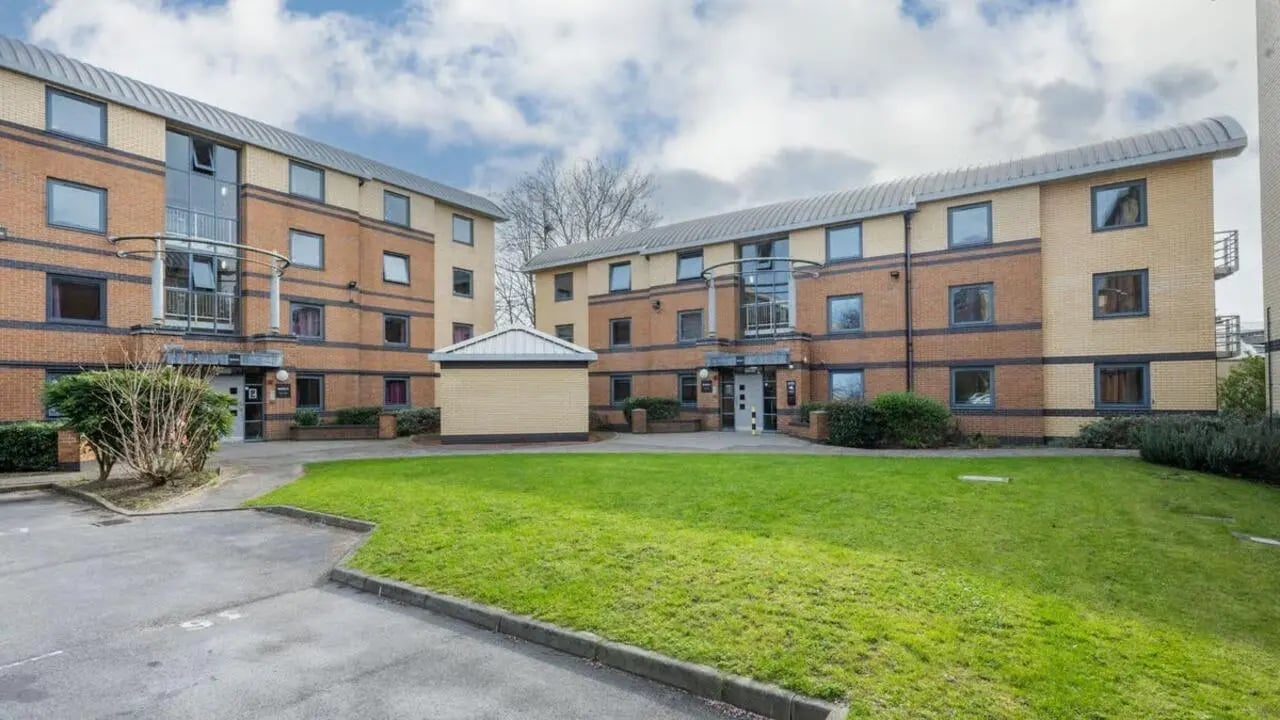 Brick apartment buildings with lawn and parking exterior at Clarence Dock Village in Leeds Student Accommodation