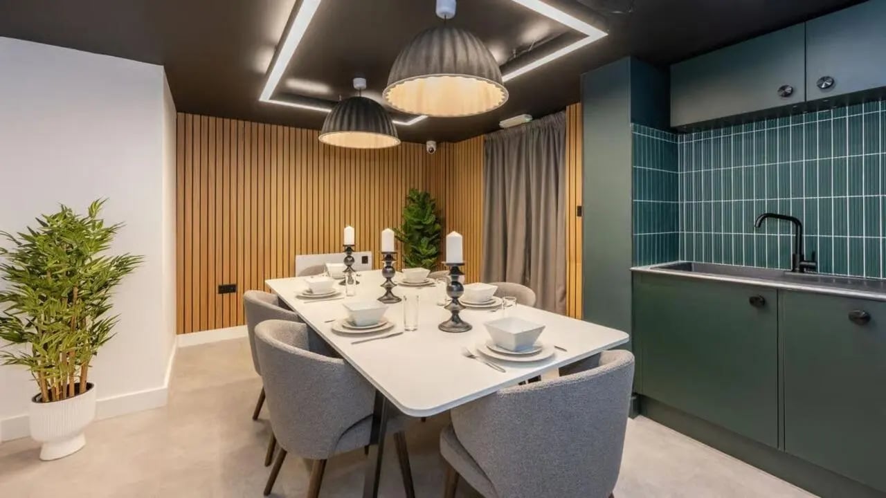 Dining table with chairs and kitchen area at Clarence Dock Village in Leeds Student Accommodation