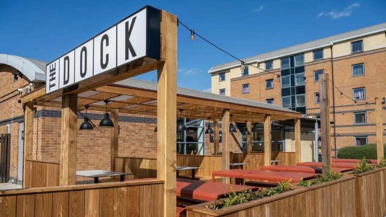 Covered seating area with tables and benches exterior at Clarence Dock Village in Leeds Student Accommodation