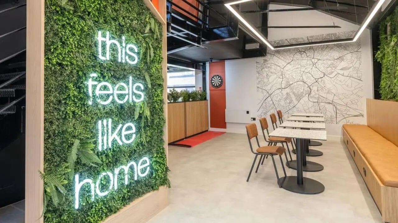 Neon sign green wall tables chairs communal area at Clarence Dock Village in Leeds Student Accommodation