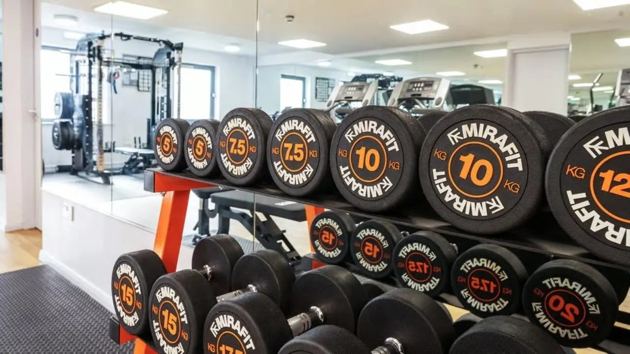 Dumbbells on rack with gym equipment in background Gym at Clarence Dock Village in Leeds Student Accommodation