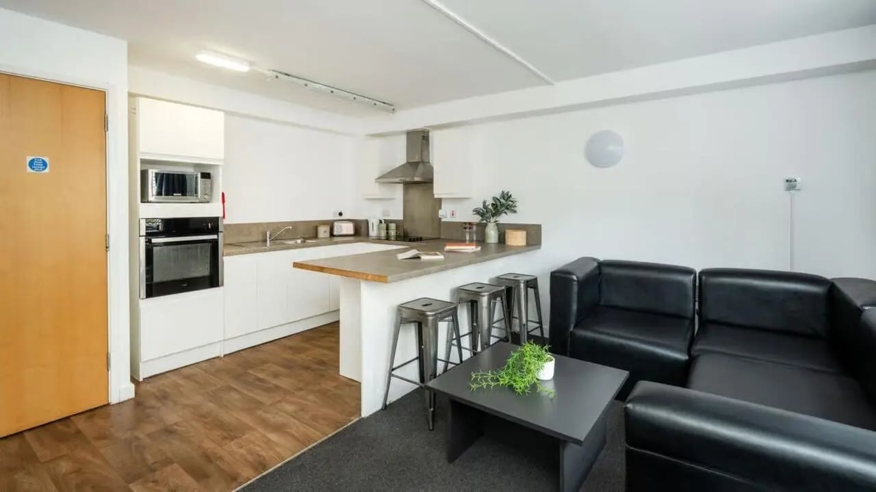 Kitchen with bar stools black sofa living room at Curzon House in Nottingham Student Accommodation