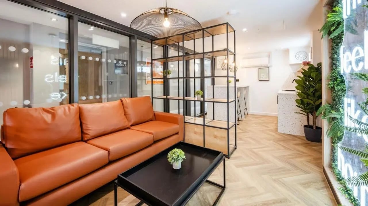 Orange sofa black table shelving kitchen area living room at Curzon House in Nottingham Student Accommodation
